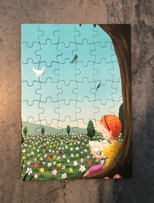 Colorful storytelling themed jigsaw puzzle featuring a child reading under a tree with flowers in the background